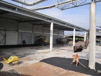 Ein Mann schaufelt Asphalt um einen Pfeiler auf dem Vorplatz