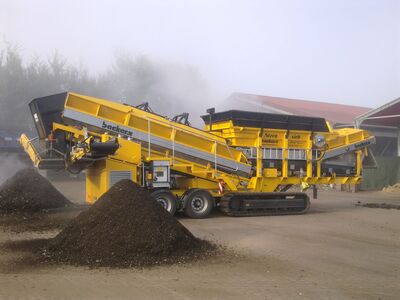 Eine Traktor-ähnliche Maschine, die mit einem Förderband ausgestattet ist und mit der Kompost gesiebt wird